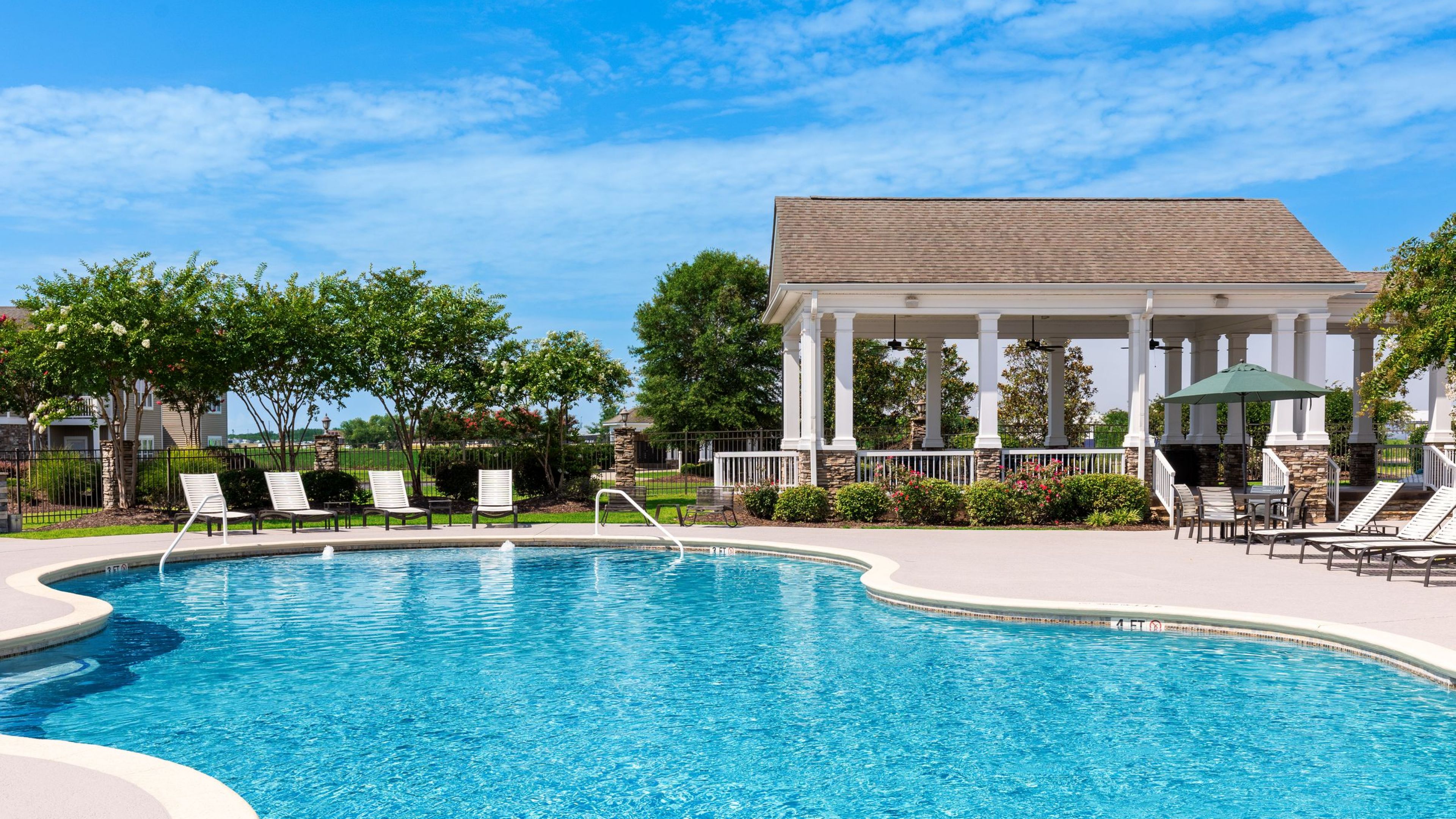 Hawthorne Crestview outdoor pool with surrounding seating and green lawn in front of leasing office building