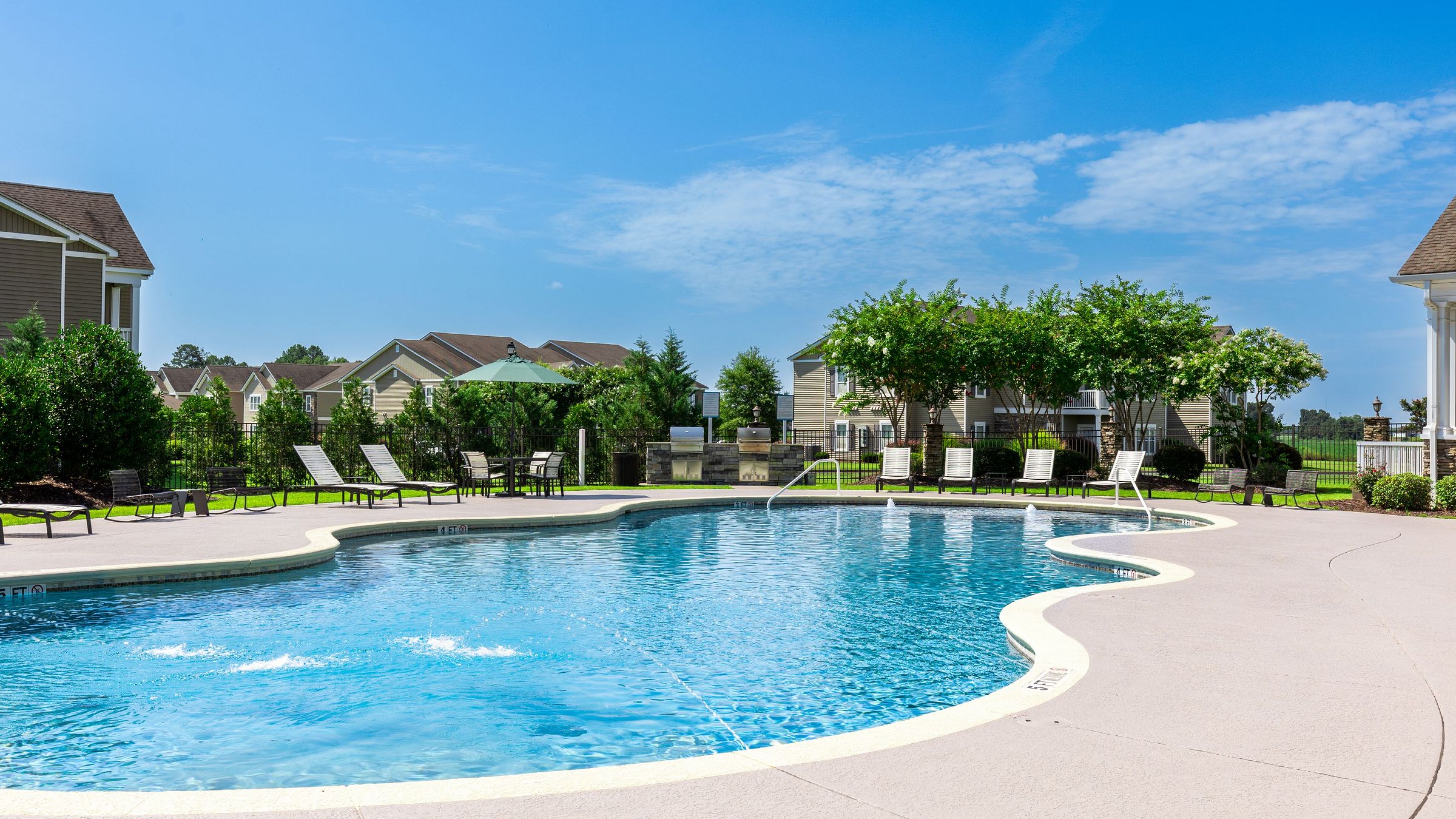 Hawthorne Crestview large outdoor pool with surrounding seating, in front of the leasing office building and outdoor pavilion